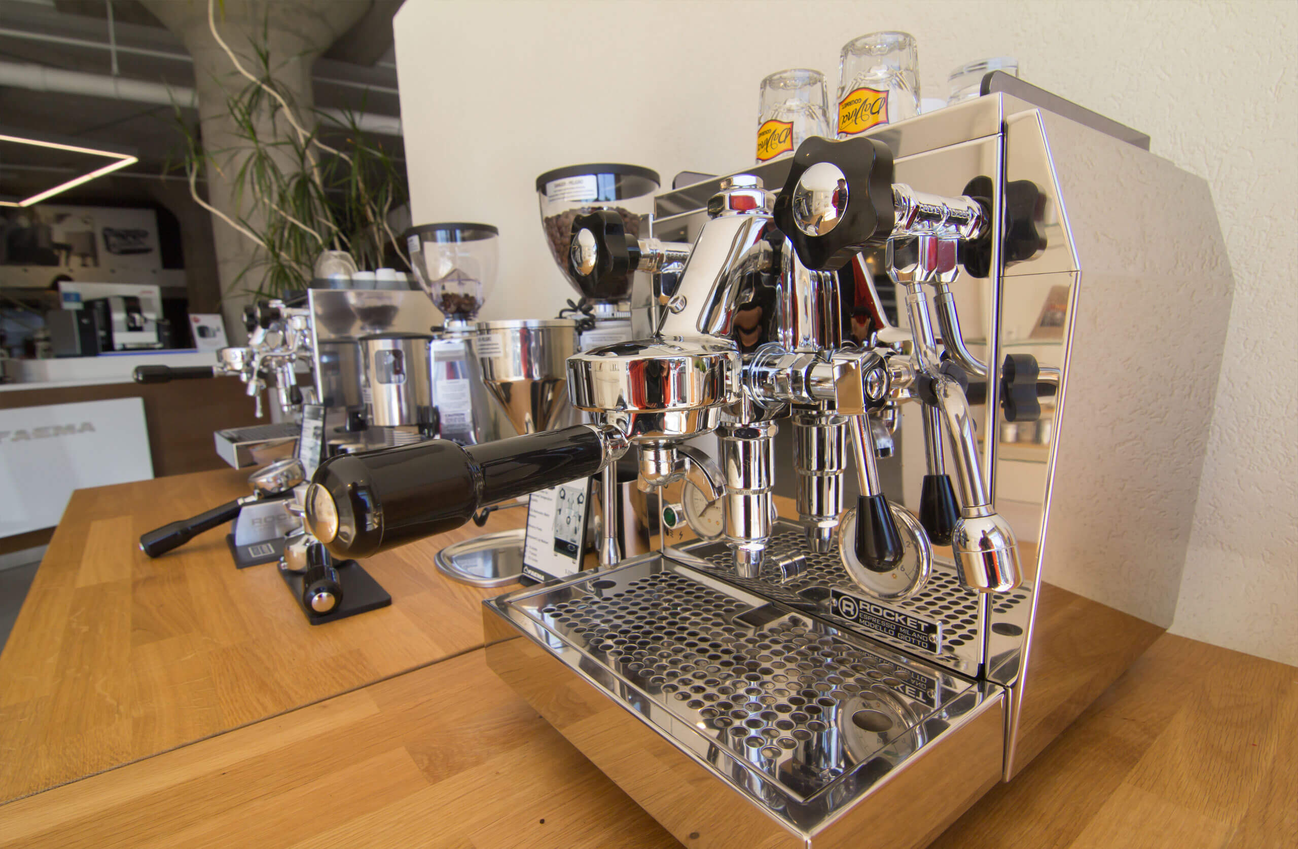 Cappuccino and espresso machines are lined on the counter top. 