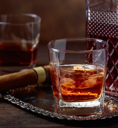 Glass of whiskey with natural ice and cigar on old wooden table. Glass of whiskey with natural ice and cigar on old wooden table.